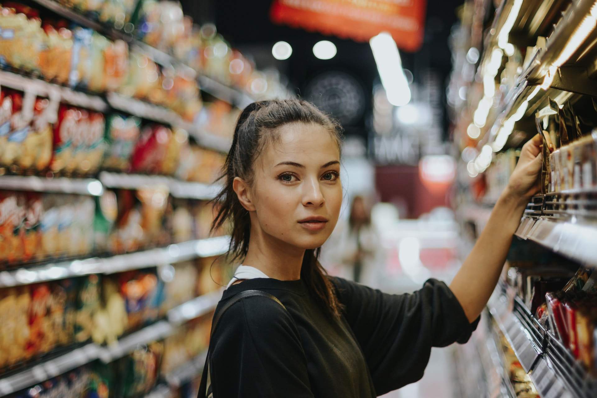 A young girl stands in a store, sharply focused, with the background blurs—a perfect example of depth-of-field photography in action.
